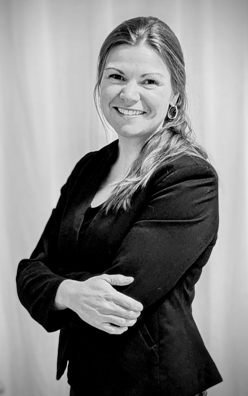 Black and white portrait of a woman wearing a suit against a plain background